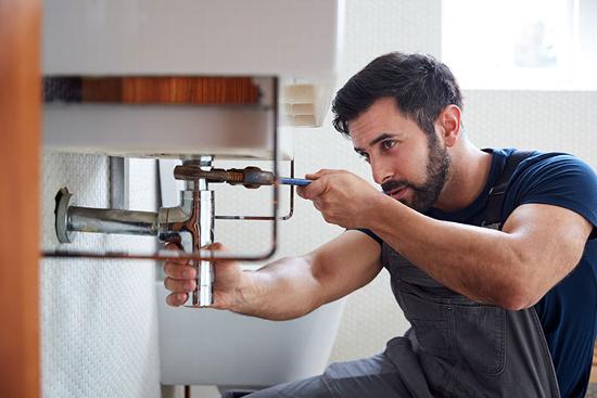plumber unblocking u-bend in bathroom sink drain